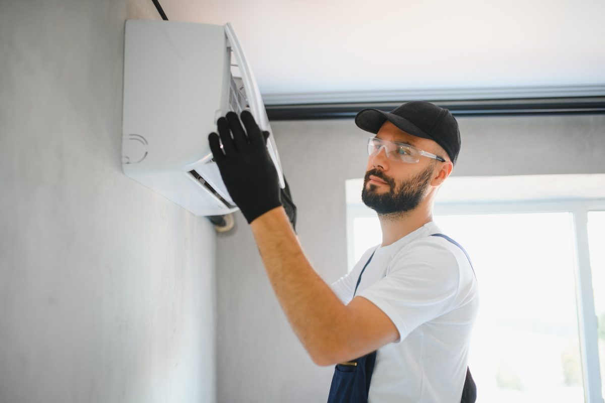 Técnico realizando cálculo de consumo ar-condicionado kWh durante instalação de split em parede