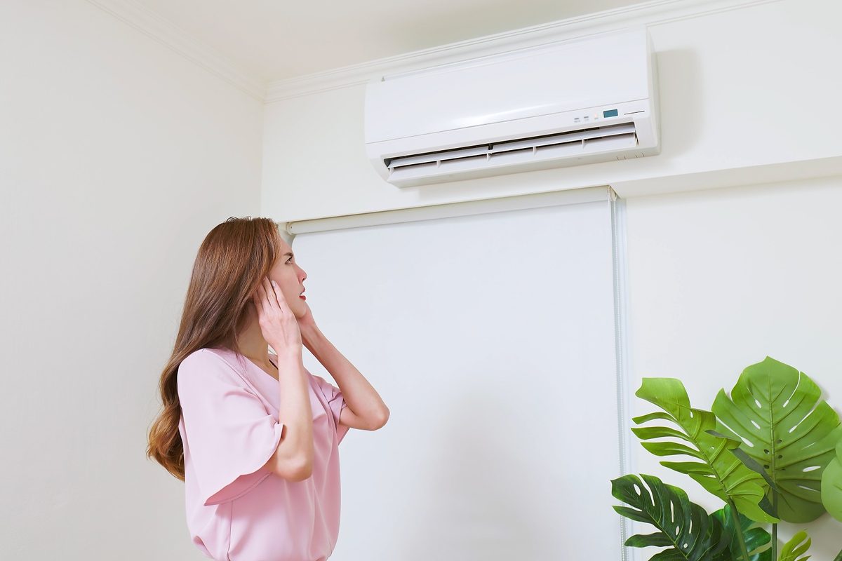 Mulher ouvindo barulho do ar-condicionado instalado na parede