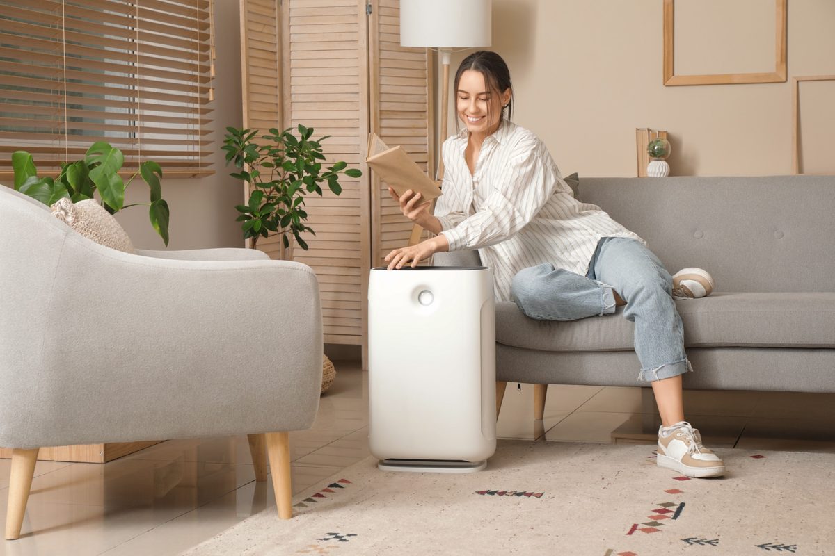 Mulher ajustando umidificador de ar em sala climatizada com ar-condicionado