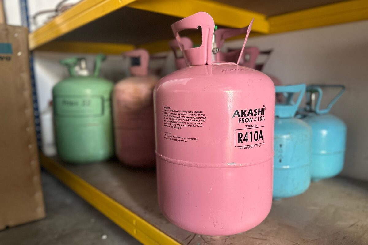 Cilindro rosa de gás refrigerante R410A armazenado em prateleira com outros cilindros ao fundo