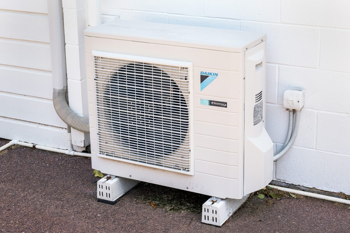 Unidade condensadora de ar-condicionado Daikin instalada na área externa de uma casa.